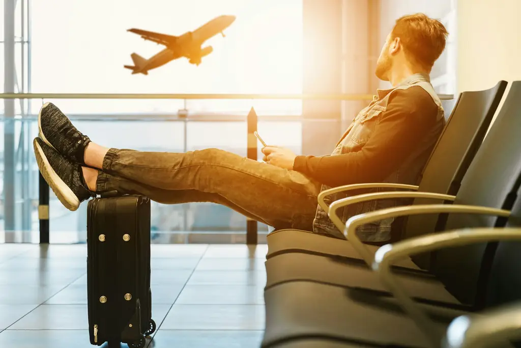 A traveller waiting in an airport lounge as a plane takes off outside